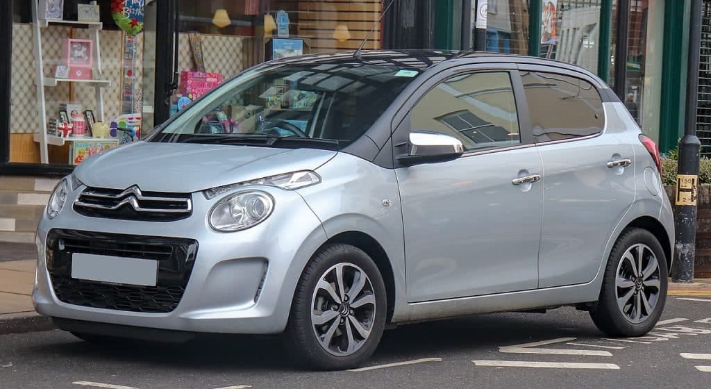 A small silver car parked on the side of a street.