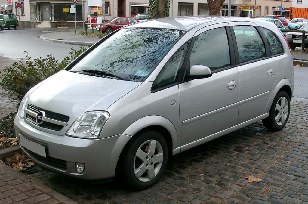 A silver car parked on a cobblestone street.