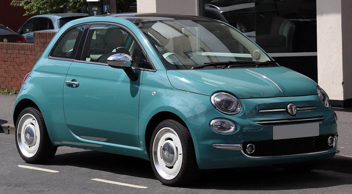 A blue fiat 500 is parked on the side of a street.