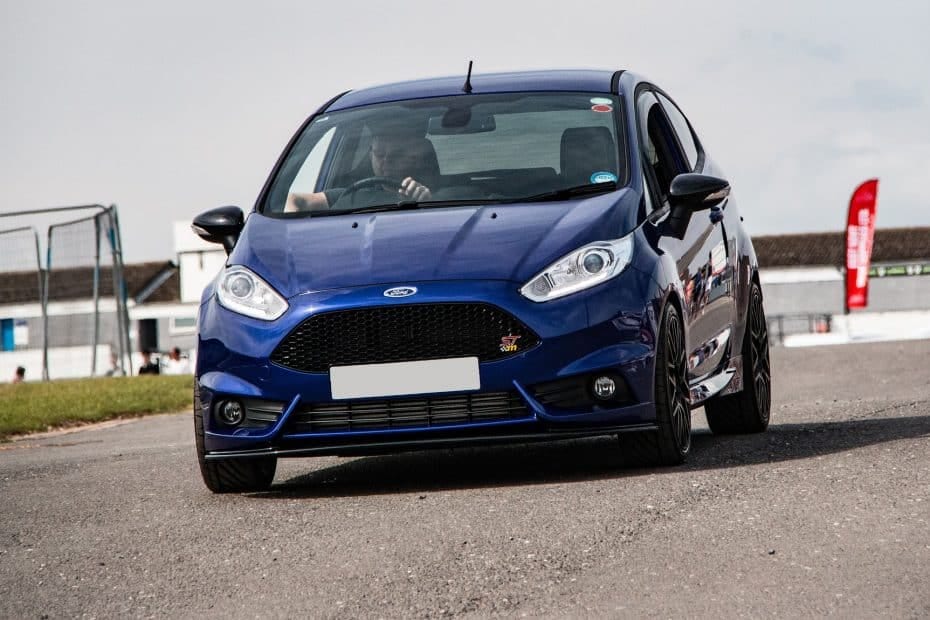 A blue ford fiesta st driving down a race track.