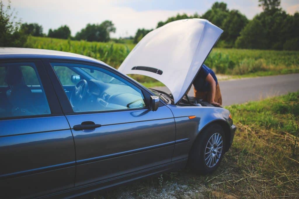 A man is looking at the hood of a car.