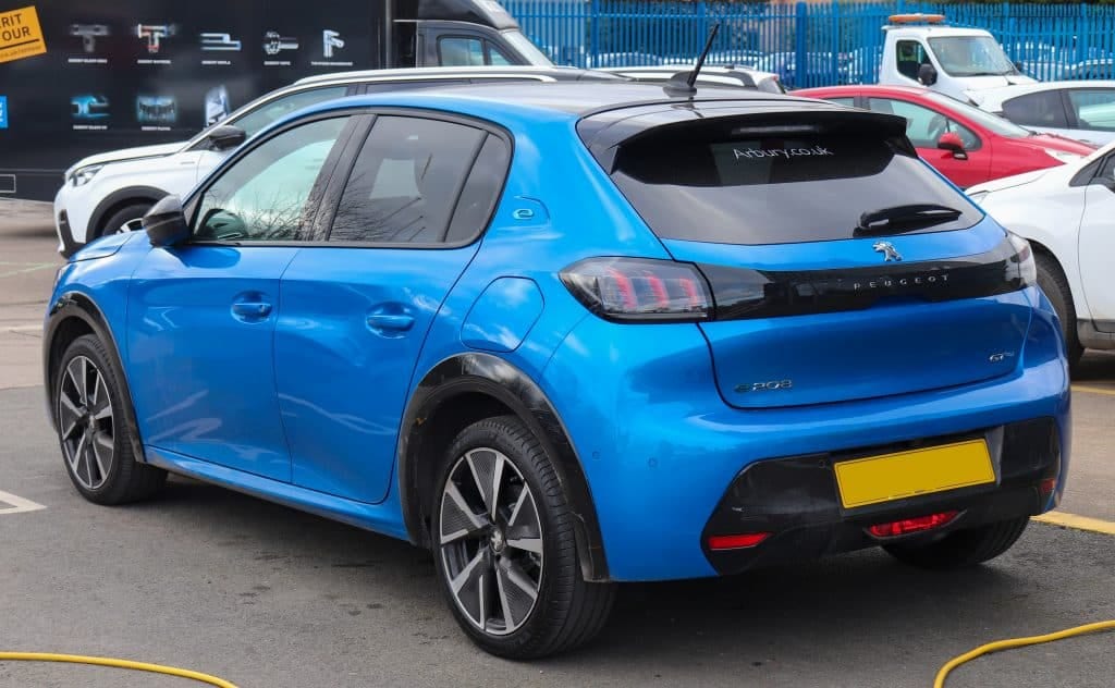 A blue Peugeot 208 parked in a parking lot.