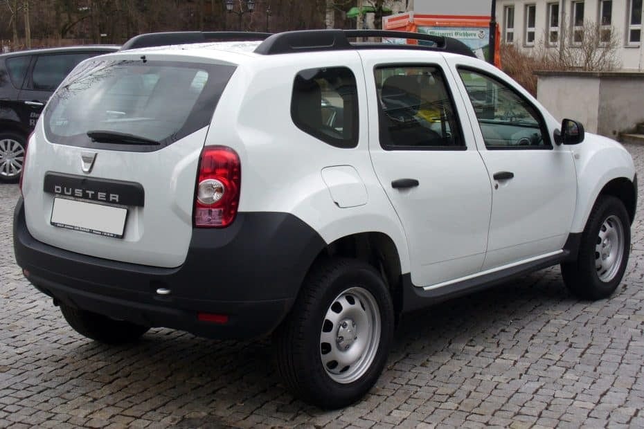 A white renault duster parked on a cobblestone street.