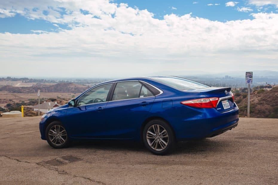 A blue toyota camry parked on a hillside.