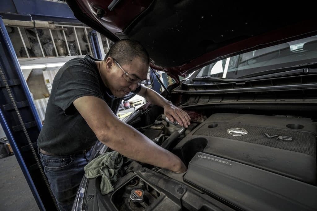 A man is working on a car under the hood.