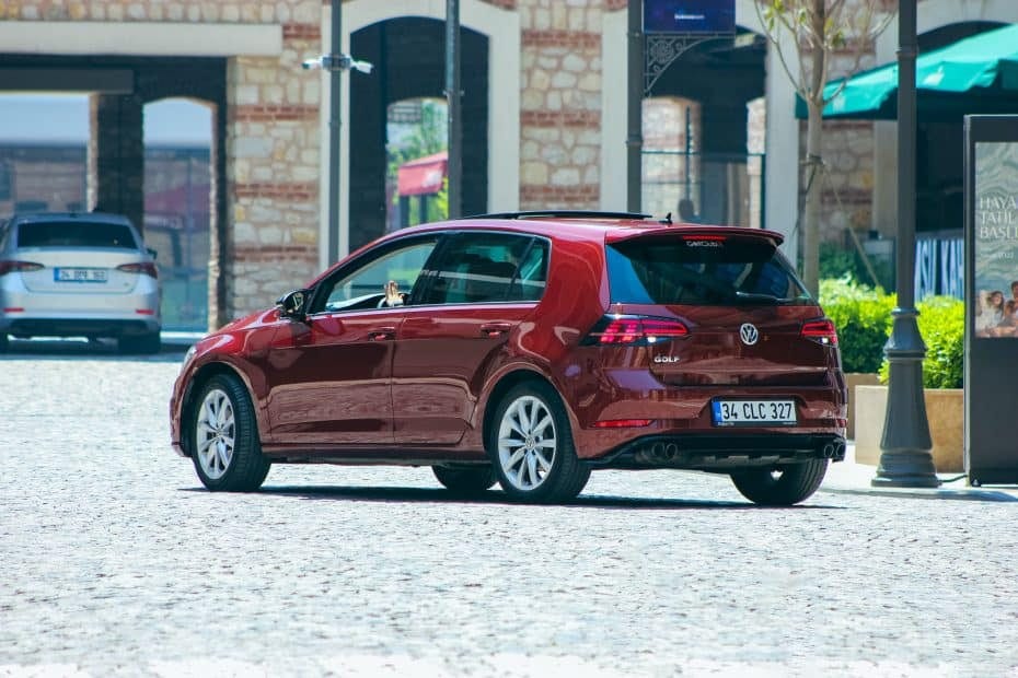A red volkswagen golf gti parked on a cobblestone street.