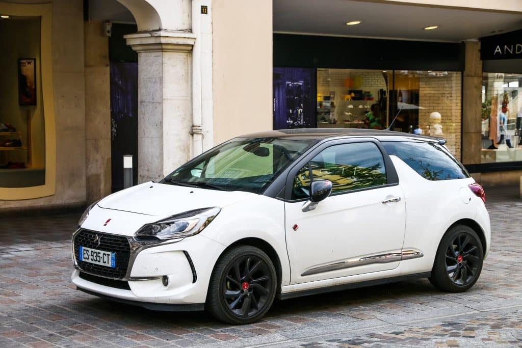 The white peugeot dci is parked on a cobblestone street.