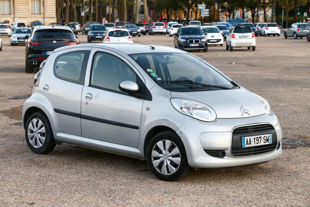 A small silver car parked in a parking lot.