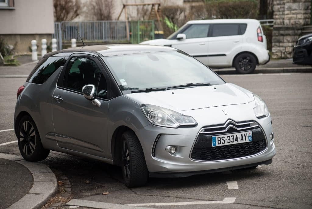 A small silver car parked on the side of the road.