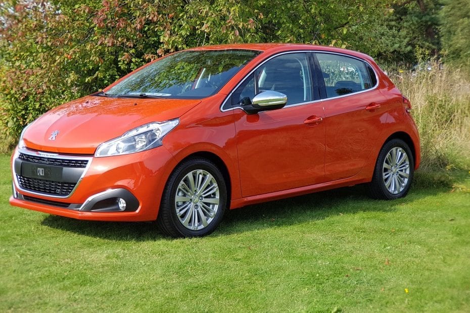 A small orange car parked on a grassy field.
