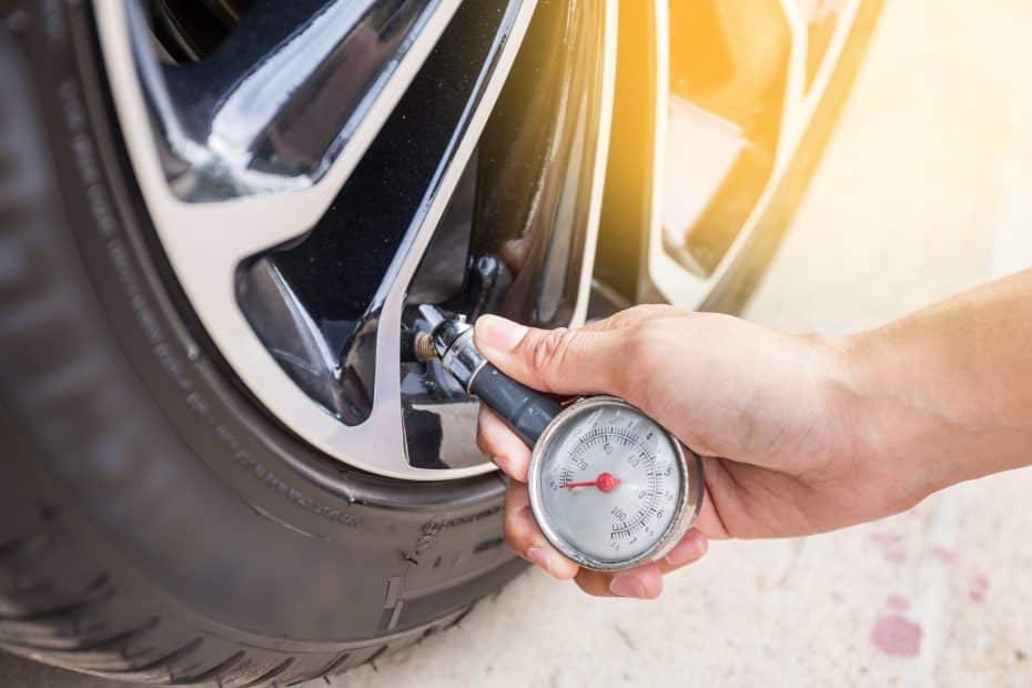 A person is checking the tire pressure of a car.