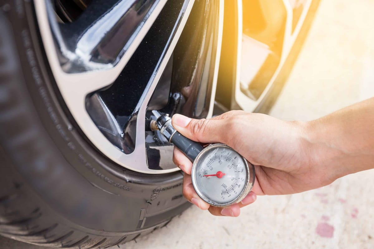 A person is checking the tire pressure of a car.