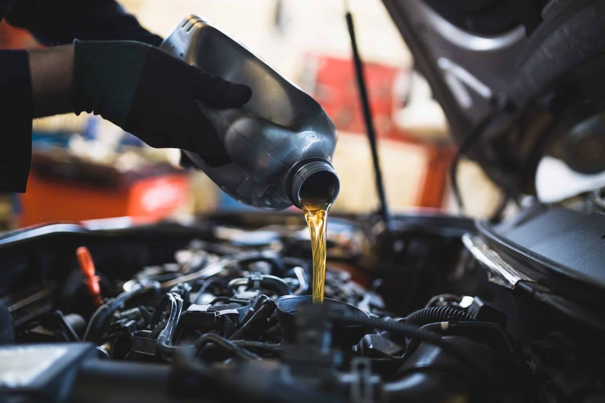 A man is pouring oil into a car engine.