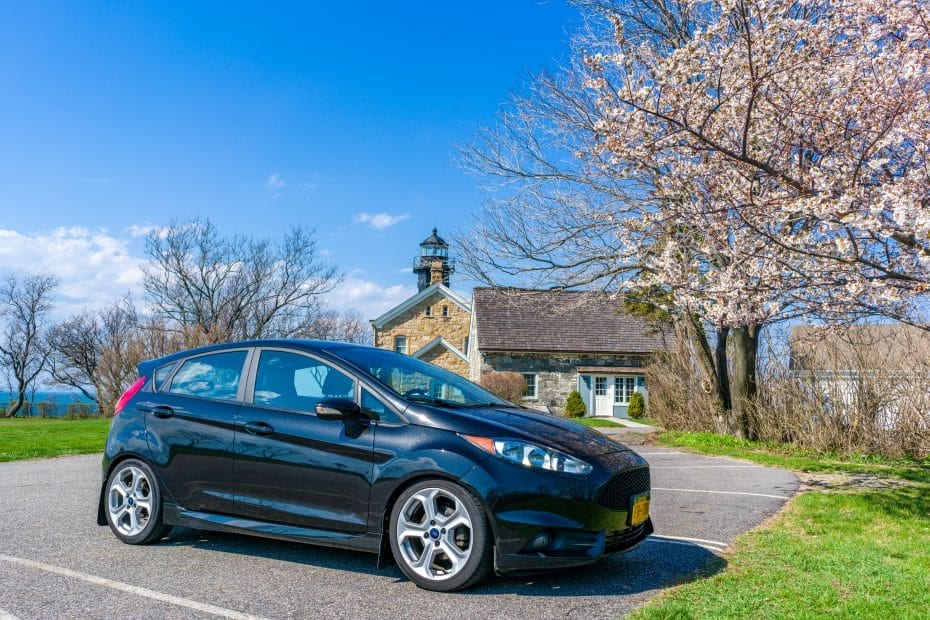 A black ford fiesta parked in front of a church.