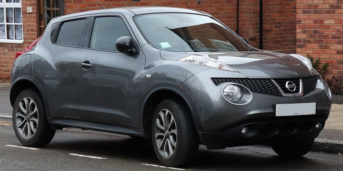 A gray nissan juke parked on the side of the road.