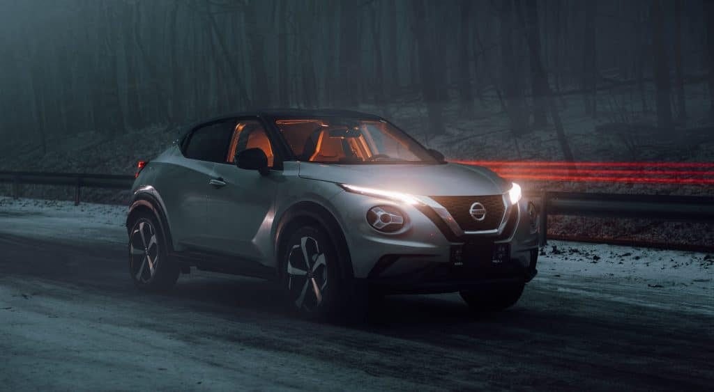 The nissan juke is driving down a snowy road.